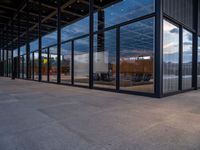 glass walls around the entrance of a modern office building, with a concrete floor underneath the glass wall