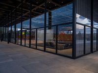 glass walls around the entrance of a modern office building, with a concrete floor underneath the glass wall