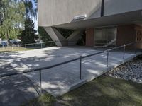 a man is walking up the steps outside of a building with a railing and concrete floor