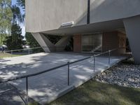 a man is walking up the steps outside of a building with a railing and concrete floor