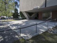 a man is walking up the steps outside of a building with a railing and concrete floor