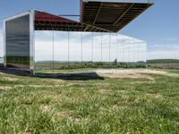 a building that is reflecting in the mirror glass at the entrance to a grassy area