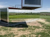 a building that is reflecting in the mirror glass at the entrance to a grassy area