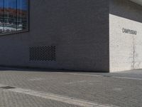 a man in yellow shirt walking on sidewalk near building with words written out to the side