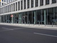 an empty city street next to a building and parked cars with double doors open on the side