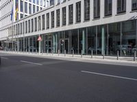 an empty city street next to a building and parked cars with double doors open on the side