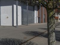 the tree in front of a gray and red building near two signs on it's sides