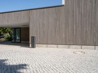 the empty walkway in front of a building has a small light post on it and two poles standing out against the wall