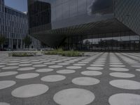 the floor of a building with a circular pattern on it in front of an angled glass building