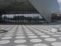 the floor of a building with a circular pattern on it in front of an angled glass building