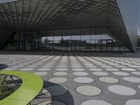 the floor of a building with a circular pattern on it in front of an angled glass building