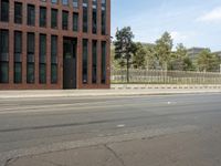 a stop light near an empty street and a fenced off area in front of buildings