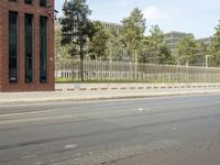 a stop light near an empty street and a fenced off area in front of buildings