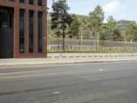 a stop light near an empty street and a fenced off area in front of buildings