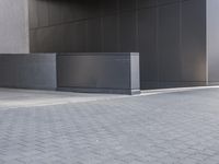 a black concrete structure and a white brick sidewalk with two steps leading to the entrance