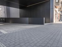 a black concrete structure and a white brick sidewalk with two steps leading to the entrance