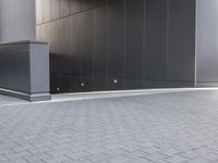 a black concrete structure and a white brick sidewalk with two steps leading to the entrance