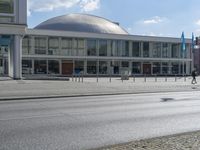 a view of a building with glass walls, on the street with people walking around