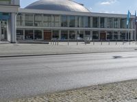 a view of a building with glass walls, on the street with people walking around