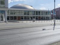 a view of a building with glass walls, on the street with people walking around