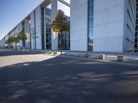 a parking lot with a sidewalk and large windows on a sunny day in the sun