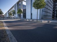 a parking lot with a sidewalk and large windows on a sunny day in the sun