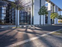 a parking lot with a sidewalk and large windows on a sunny day in the sun