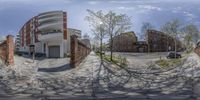 a fish eye lens is taking a photo of a paved area and buildings and a car