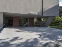 a view of a sidewalk with a building behind it that has a door way in front