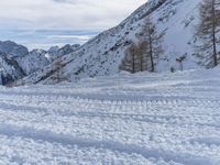 a snowy road with skis on it next to mountains under a blue sky with white clouds