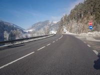 an empty highway with snowy mountains in the background, at the edge of a mountain range