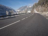 an empty highway with snowy mountains in the background, at the edge of a mountain range