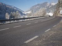 an empty highway with snowy mountains in the background, at the edge of a mountain range