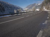 an empty highway with snowy mountains in the background, at the edge of a mountain range