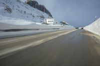 a speed moving view of a snowy road and snow covered mountains from inside the car