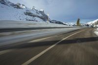a speed moving view of a snowy road and snow covered mountains from inside the car