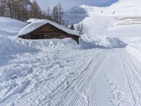 a cabin is surrounded by many piles of snow on the ground in front of a ski slope