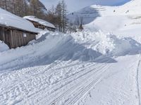 a cabin is surrounded by many piles of snow on the ground in front of a ski slope