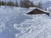 a cabin is surrounded by many piles of snow on the ground in front of a ski slope