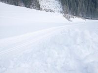 a skier is riding across the snow in the mountains side country road and near a house