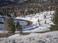 a winding road in the middle of a mountain covered in snow with trees and mountains