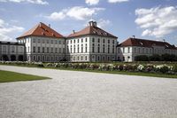 an exterior view of two white buildings with turrets on top of them and lawn and manicured paths