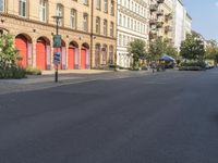 an empty street with buildings in the background and street lamps on each side, and red garage doors open