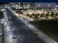 a long highway is empty in front of buildings at night time, with lights illuminating the road