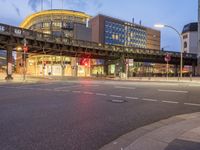 there is an empty street with traffic at twilight on the corner of this street and the building behind it