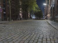 a brick street with no cars in it at night time, lit by streetlights