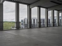 a photo of a parking lot through an enclosed area with many windows and a fence