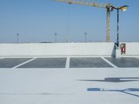 a parking lot covered in concrete next to a crane and a construction crane in the distance