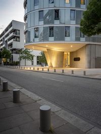 a building with several lights on it's outside near a street with a curb