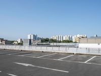 an empty parking lot with multiple cars parked in it in front of the city skyline